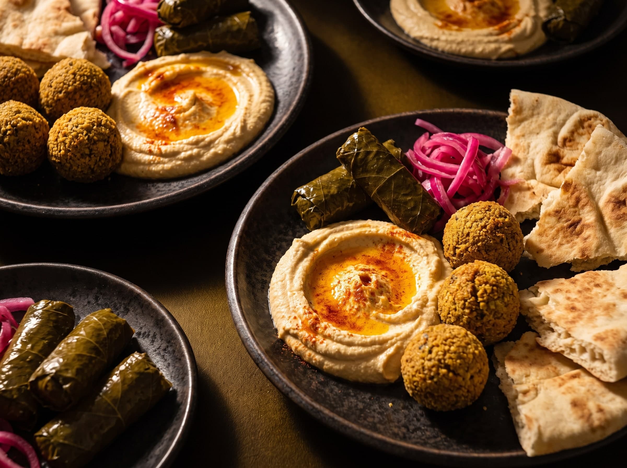 Hummus mit Paprikaöl, Falafel, gefüllte Weinblätter, eingelegte Zwiebeln und Fladenbrot
